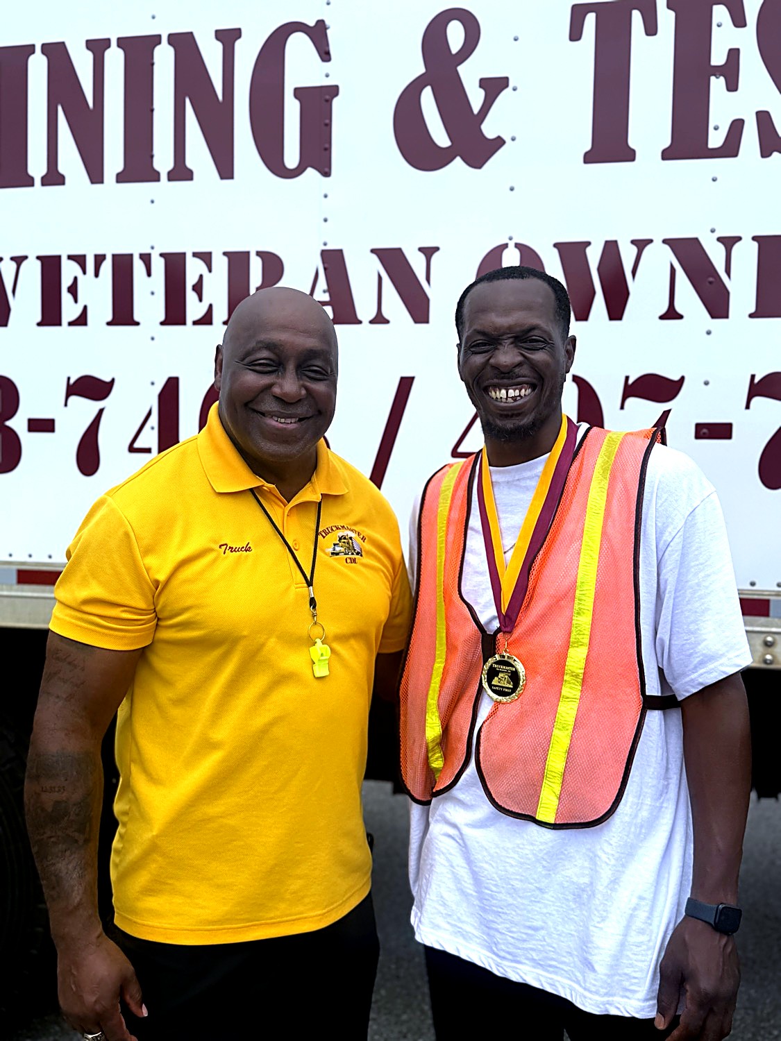 Owner Byron Simpson celebrating with a smiling TruckMaster CDL graduate wearing a Safety First medal