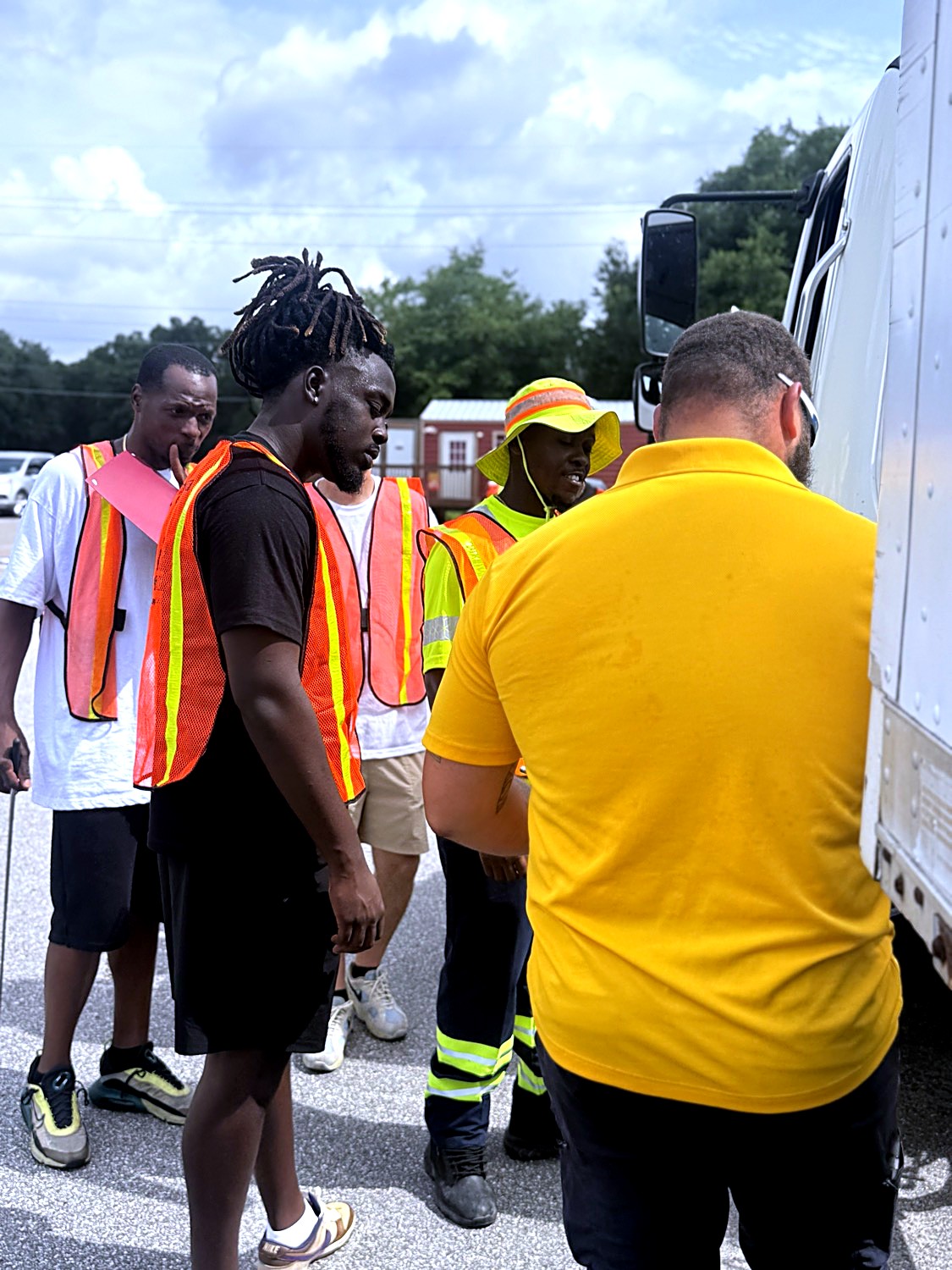 TruckMaster instructor coaching a group of CDL students in safety vests beside a truck